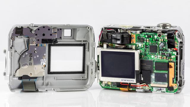 Geöffnetes Gehäuse. Links die Rückseite der vorderen Abdeckung, rechts die eigentliche Kamera mit Display und Platine