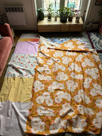 Un grand drap de 2,40 m x2,80 m, fait de plusieurs tissus différents. Il est étalé par terre et prends toute la place libre de mon salon.. Dans les tons jaunes, roses, fleuris.