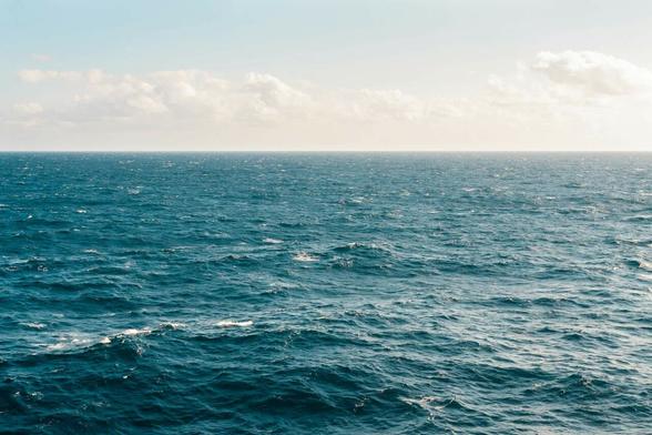 Du premier au dernier plan, de l'eau. Quelques nuages viennent habiller le ciel d'une légère brume. Les ridules de l'océan sont vêtues des bourrasques de vent qui viennent blanchir les crêtes des vagues.