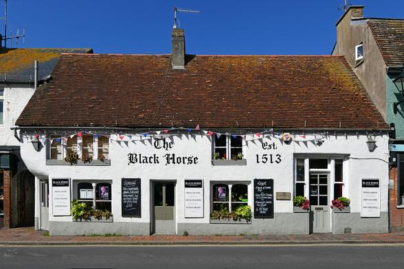 Photo of a rendered, timber-framed building thought to be C16, now a public house. Tiled, hipped roof running parallel to High Street. Jettied upper-storey to the south entrance. Grade 2 listed. Rottingdean