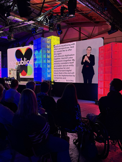 Karsten Wildberger auf der Bühne der republica, gedolmetscht auf großem Screen in Englisch und Gebärdensprache