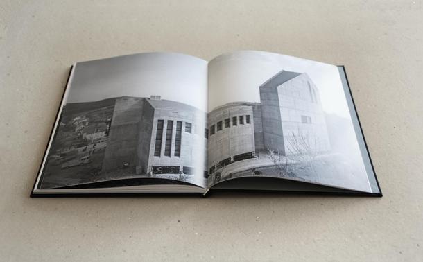 Foto eines aufgeschlagenen Buches. Die Doppelseite zeigt das Schwarzweißfoto einer Betonkirche.
