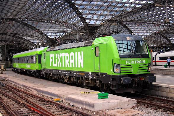 Der Flixtrain von Aachen nach Berlin fährt in Köln Hbf ab. Vorne fährt eine moderne Siemens Vectron Elektrolokomotive, mit einigen kürzlich generalüberholten Waggons.