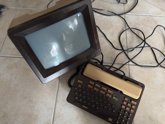 Un Minitel M10 avec l’écran cathodique d’un côté et un combiné téléphonique à clavier AZERTY de l’autre.