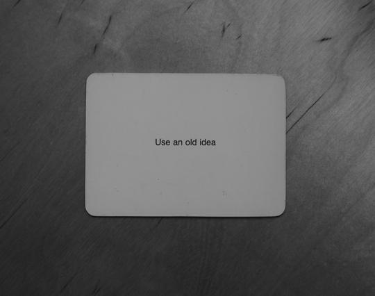 A black-and-white photo of an Oblique Strategy card. The card reads: 'Use an old idea'.