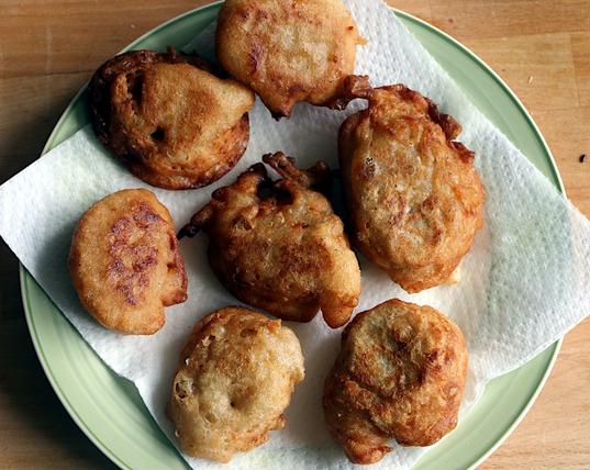 Golden brown fritters on paper towel a plate.  They're made by dripping spoonsful of discarded sourdough starter into hot frying oil.