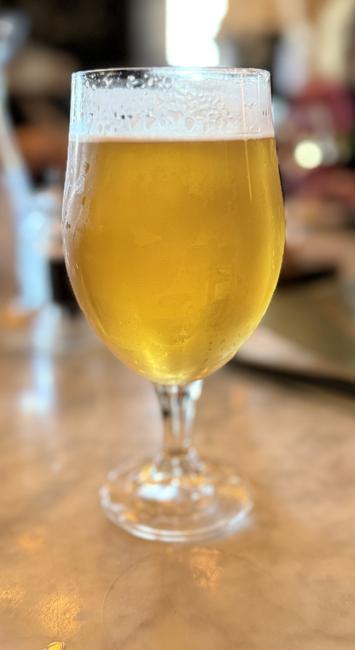 A tall tulip glass full of light amber lager