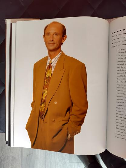 Derpy early to mid 90s American, definitely American, designer wearing a slouchy oversized camel colour, double breasted, suit and a fucking mad tie. Shirt buttoned up.