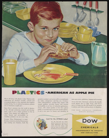 A young boy appears to be using his hands to eat a pie. He surrounded by yellow green and blue plastic dishes, cups, and saucers, and a pitcher.