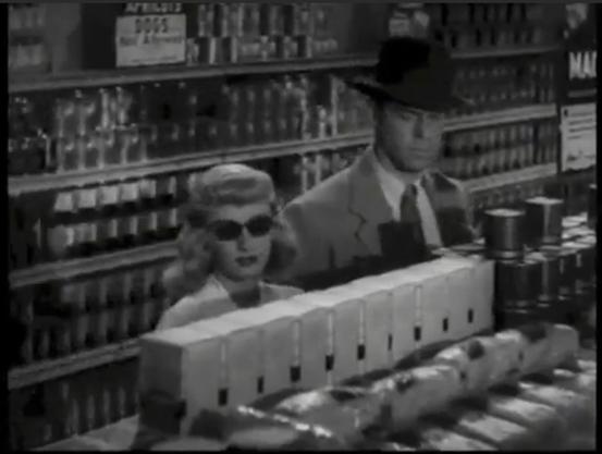 Murderous couple — femme fatale Phyllis (Barbara Stanwyck) in sunglasses and Neff (Fred MacMurray) — conspire in the canned goods isle at Jerry’s Market in Double Indemnity