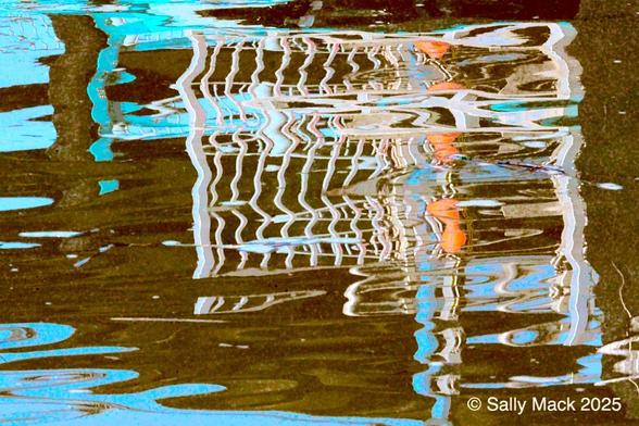Color abstract photo of a white railing reflected in slightly moving water, making the reflection wavy. Background is a mixture of colors including brown, turquoise, and blue with orange mixed in the railing on the right side.