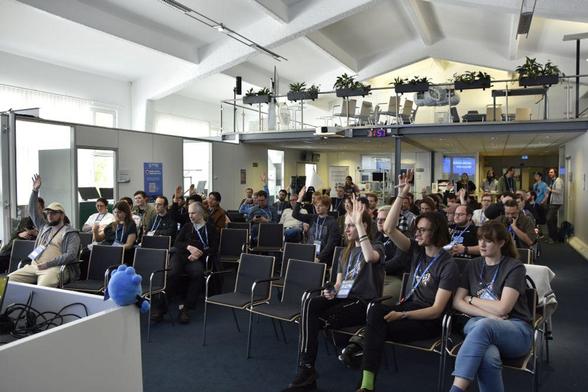 People during session planning, rasing hands to show that they would like to attend a session