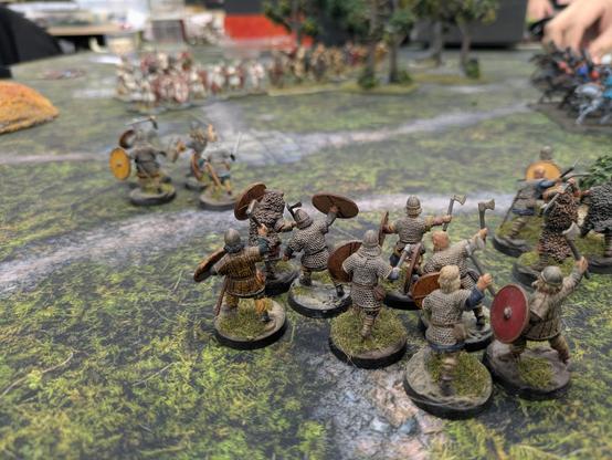 A group of miniature vikings seen from the back, charging into battle on the tabletop.