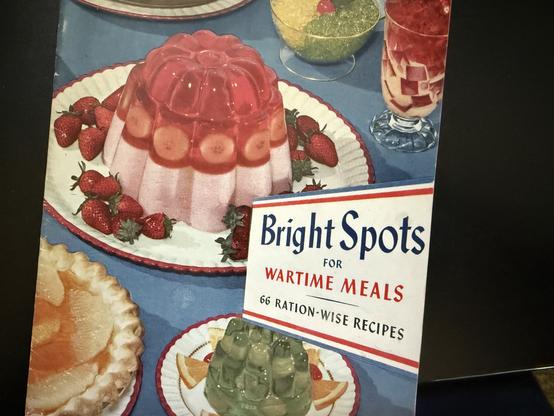Cover of a booklet, Bright Pots for Wartime Meals, 66 Ration-Wise Recipes, from the makers of Jell-O, picturing various dishes made with Jell-O gelatins and puddings.