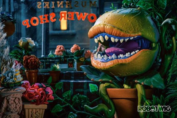 Audrey II in Mushniks Flower Shop mouth open surrounded by flowers. Outside its dark and you can see houses across the street