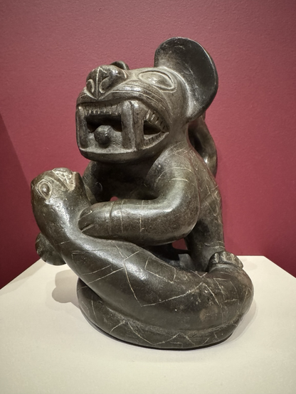 photo of Moche feline with snake blackware effigy vessel #1 at The Walters  label at museum: “Feline Effigy Stirrup-Spout Vessel Unidentified artists), Moche culture, Peru, 500-800 CE Earthenware Anonymous gift, 2009, acc. no. 48.2843”