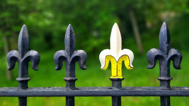 A Victorian railing with fleur-de-lis decorations on the top, one of which has been painted to look like a half-peeled banana.