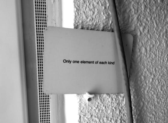 A black-and-white photo of an Oblique Strategy card. The card reads: 'Only one element of each kind'.
