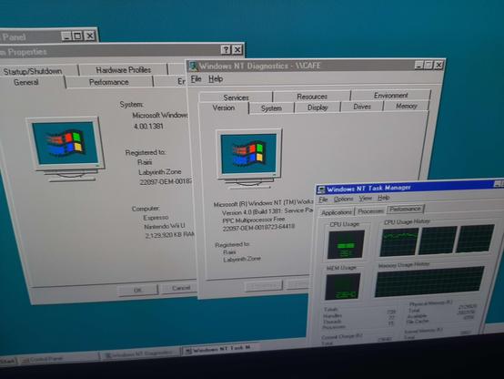 a picture of a tv screen showing an NT 4 desktop with four windows open:
control panel in the background not visible
system properties, showing CPU "Espresso", system "Nintendo Wii U", 2,129,920KB RAM
winmsd, computer name CAFE, showing "PPC Multiprocessor Free"
task manager, showing 3 CPUs, with 26% CPU usage and that being mainly ~80% usage of CPU 0