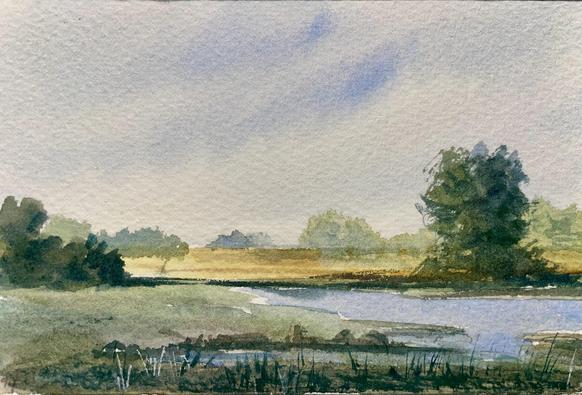 A quiet stream curves through a marshy field, bordered by patches of grass and scattered trees, with soft light filtering through a hazy sky that suggests early morning or late afternoon calm.