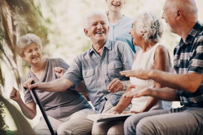 Two elderly white couples sitting on a bench outside