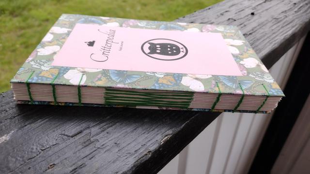A side view of the spine. At the two edges, the book is held together with coptic style chain stitches, and the center features a French Link which looks like an intertwined ladder