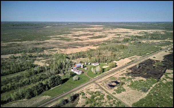 Aerial photo of barn with large wetland in background. In foreground, some patches of vegitation appear to have been recently burned.