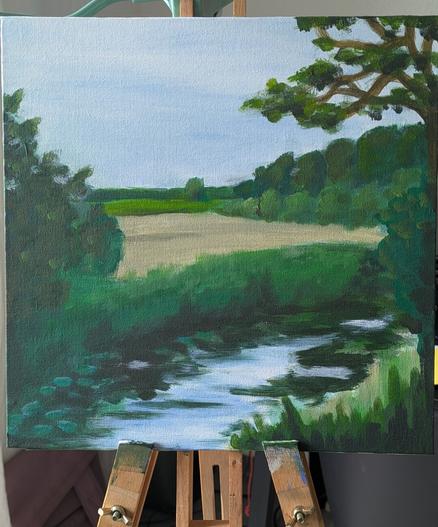 A creek in front of fields an meadows. A row of trees in the background. The painting is square and still on the easel.