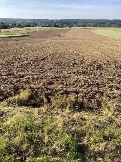 Un champ en court de travail, le tracteur tout petit dedans et la lumière de fin de journée. Au fond la ligne d’arbres qui borde la Dordogne.