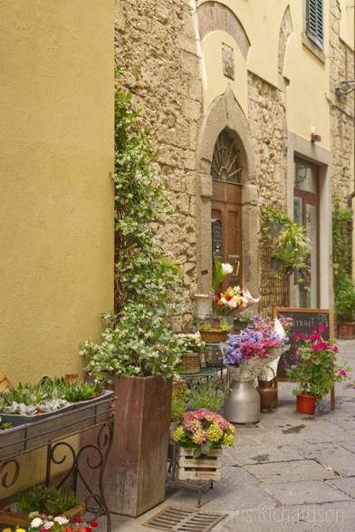 A beautiful old yellow building in Prato, Italy, with a flower shop.