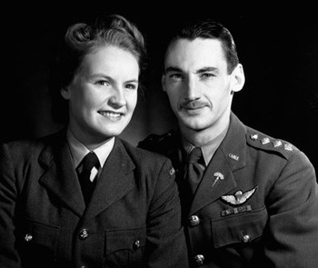 Photo of Sonia Butt and her husband, and fellow SOE agent, Guy D'Artois. They are both in their military uniform. Sonia is a white woman with blonde hair. He's a white man with dark hair and a moustache. This was taken on their wedding day, weeks before they were sent to France.