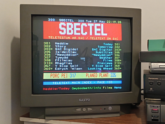 Sanyo CRT TV showing an old teletext page from Sbectel, S4C's teletext service.

P300 SBECTEL 300 Tue 27 May 22:19.28

TELETESTUN AR S4C / TELETEXT ON S4C
301  Heddiw                  Today 301
302  Yfory                Tomorrow 302
303+ S4C Digidol    S4C Digital 303+
305  Is-deitlau          Subtitles 305
306  "Newyddion"       "Newyddion" 306
307  Tywydd                Weather 307
308  Ffilmiau                Films 308+
310+ Rhagflas             Previews 310+
357  Y Sioe Gelf       Y Sioe Gelf 358
360+ Edrych 'mlaen   Looking Ahead 360+

PORC PEI 317     PLANED PLANT 335

TELETEXT MAIN INDEX - PAGE 100

Heddiw/Today Gwybodaeth/Info Films Heno