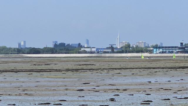 View across tidal mudflats towards the city of Portsmouth, with its distinctive Spinnaker tower.