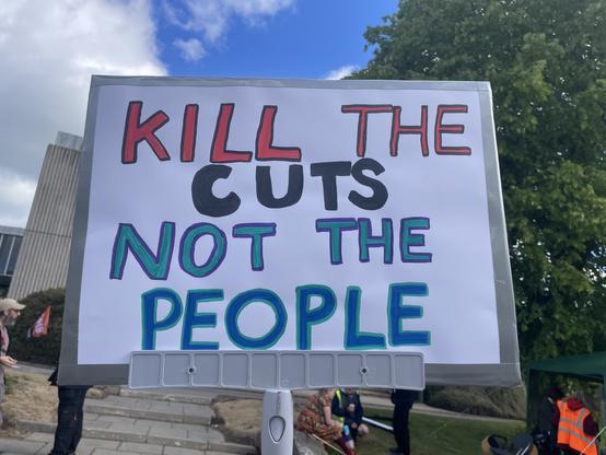 Placard that says “kill the cuts not the people”