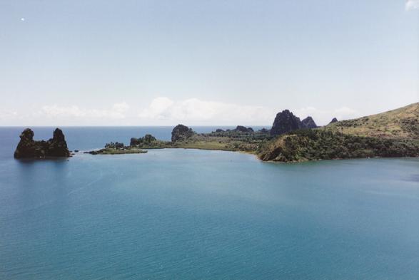 Vue de l'océan en Nouvelle-Calédonie, avec une langue de terre qui se termine avec un rocher présentant deux protubérances.