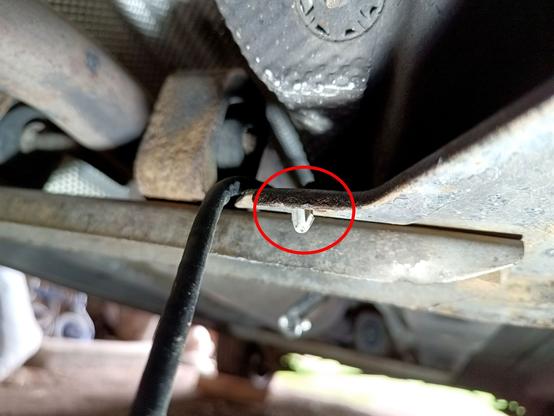 Close-up of a grey plastic clip that was supposed to be holding said cable. The cable dangles next to it, only the bottom part of the clip is still there. It's circled in red.