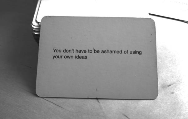 A black-and-white photo of an Oblique Strategy card. The card reads: 'You don't have to be ashamed of using your own ideas'.