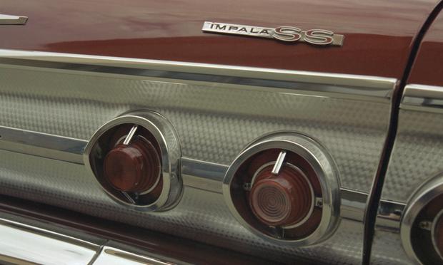 Closeup photo of a vintage automobile, with the right rear turn signal lighting dominating the image. A badge reads, "Impala SS."