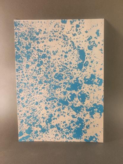 A photo of a white print on blue paper. It shows a bubbley pattern.