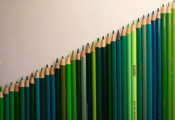 lots of different green crayons placed so they form a line gowing up from the bottom-left to the top-right