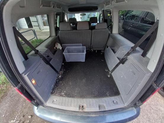 Leerer Kofferraum eines VW Caddy, mit Weitwinkel fotografiert. Der Boden ist etwas krümelig, eine leere Plastikkiste steht im Kofferraum.