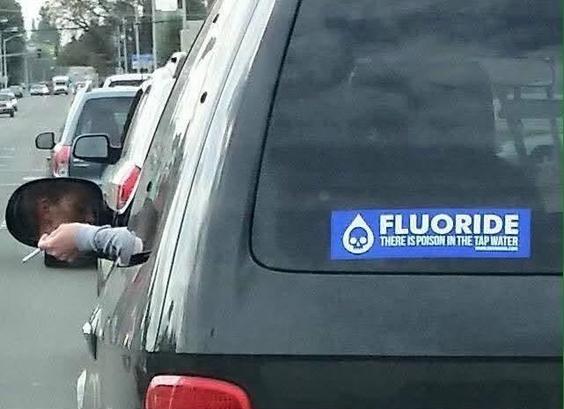 A bumper sticker on an SUV reads “FLUORIDE 
THERE IS POISON IN THE TAP WATER”

The driver’s hand can be seen hanging out of the window holding a cigarette.