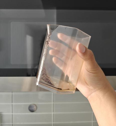 I'm holding up an aeropress jug with a small trail of coffee grounds, starting wide at the bottom and forming a narrow path to the top of the jug at the beak