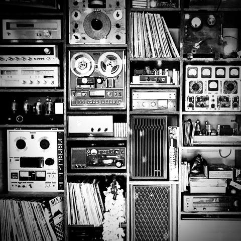 Black and white photo of a wall with an assortment of vintage audio equipment.