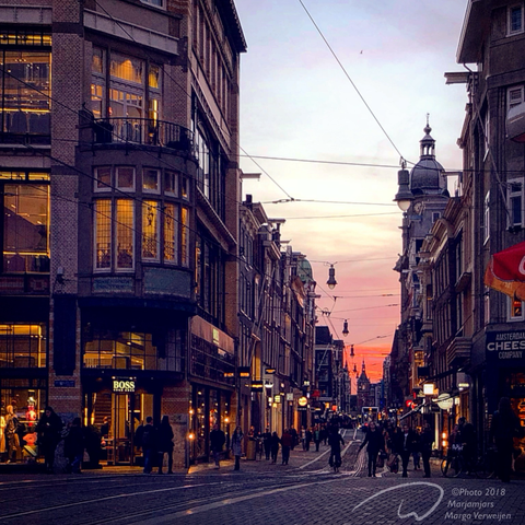 Small street with old houses in Amsterdam at sunset. A bloodred sky and the window glasses reflecting a gold color.