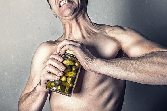 skinny muscled man trying to open pickle jar
