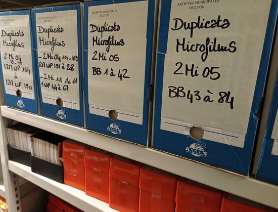 Photographies numériques couleur portrait et paysage pour l'ensemble du fil.
Des boîtes d'archives et des boîtes en plastique noir ou orange. Sur les boîtes d'archives, il est noté "duplicata microfilms", la cote de type 2MI 05 et les cotes de documents originaux qui sont reproduits.