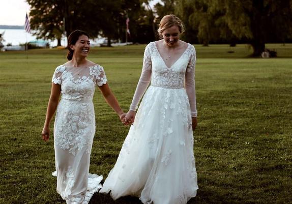 A beautiful photo of Rachael Lippincott and Alyson Derrick holding hands in their wedding dresses.