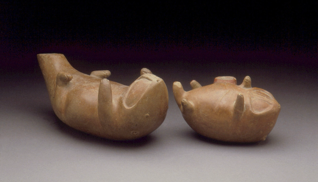 official museum photo, pair of small otter sculptures on their backs, molded and incised details