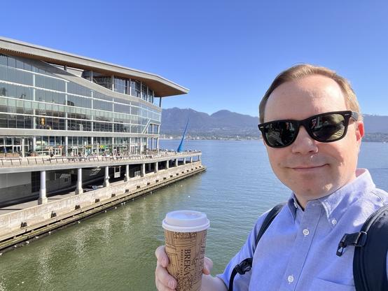 Chad selfie in front of the Vancouver Convention Center holding a coffee on a gorgeous clear day
